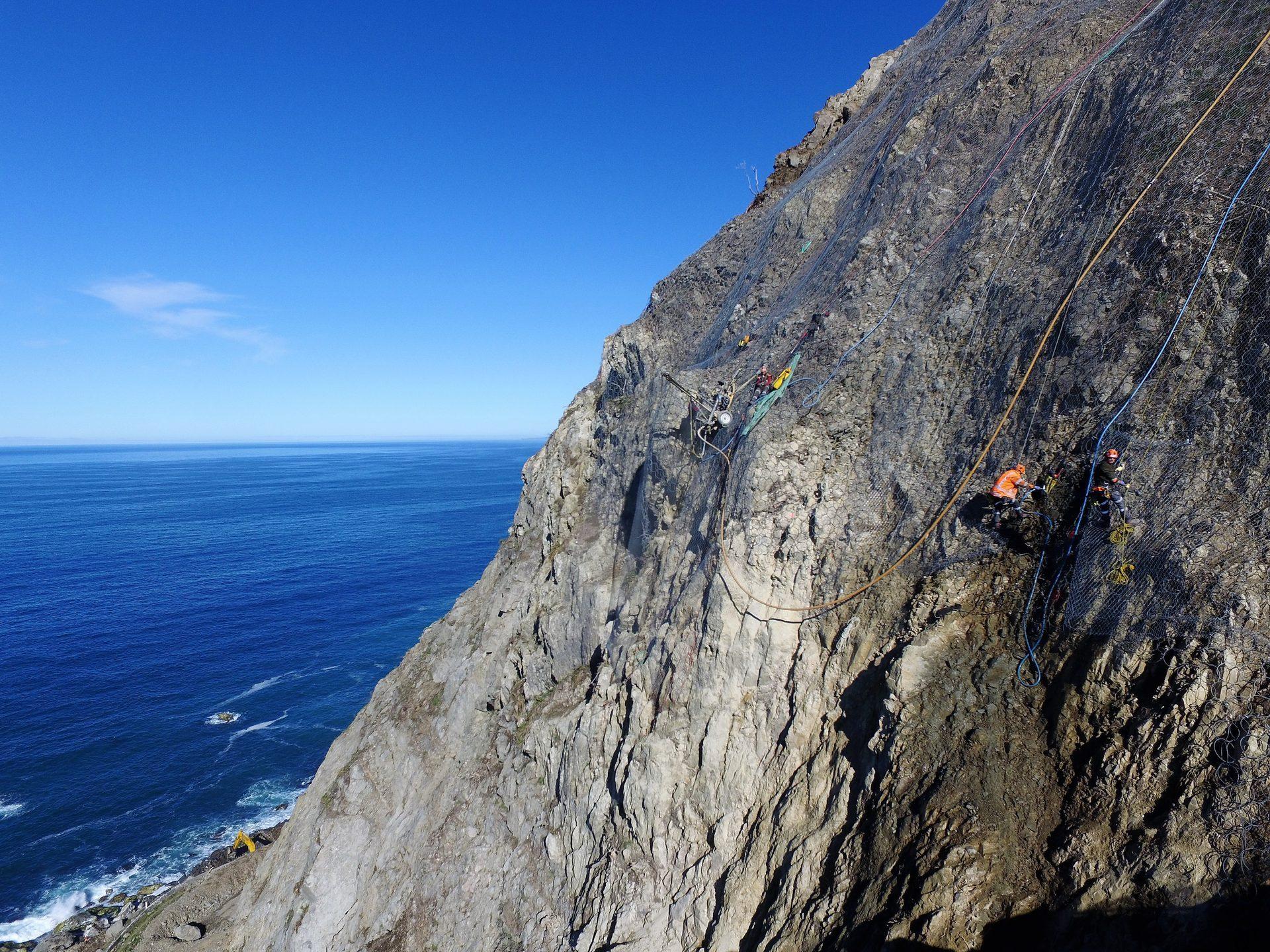 NZ West Coast coastal road at sunset beneath an unstable cliff face