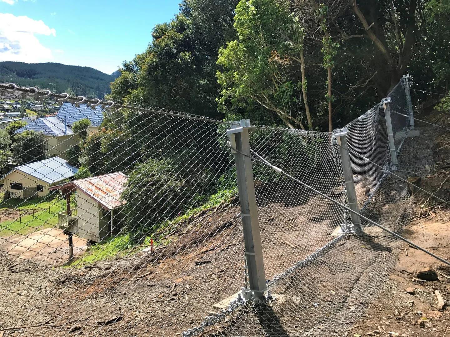 Rockfall catch fence protecting a residential area below a coastal slope